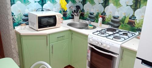 una cucina con forno a microonde e lavandino di Темиртау 7 микрорайон 1а a Temirtaū