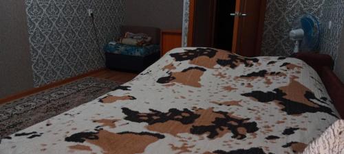 un letto in una camera da letto con una coperta per mucche di Темиртау 7 микрорайон 1а a Temirtaū