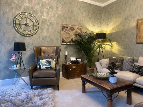 a living room with a couch and a clock on the wall at Park View is a beautiful whole entire house close to town centre, sleeps 8 in 4 rooms, 2 doubles and 4 single beds with 2 shower rooms, available for holidays, insurance stays, trades people, contractors, pets welcome in Wisbech