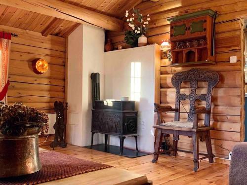 a wooden room with a stove and a chair at Sjarmerende tømmerhytte på gårdstun in Baukål