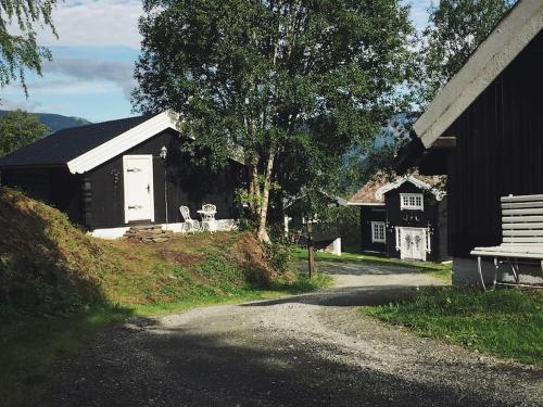 a black building with a bench and a house at Sjarmerende tømmerhytte på gårdstun in Baukål
