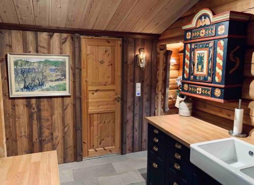 a bathroom with a sink and a wooden wall at Sjarmerende tømmerhytte på gårdstun 