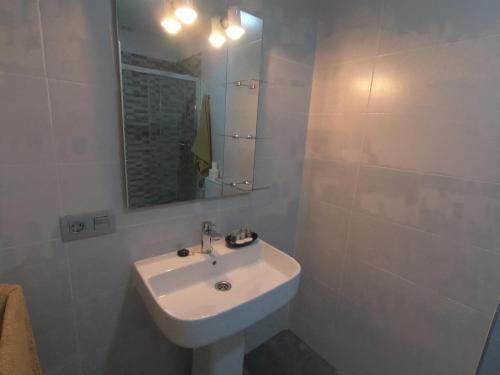 W białej łazience znajduje się umywalka i lustro. w obiekcie Tinérfe el grande 12 w Adeje