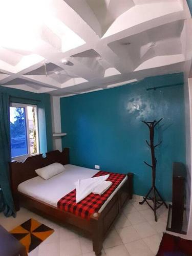 - une chambre avec un lit et un mur bleu dans l'établissement Sasha Holiday Apartments #B5, à Mtwapa