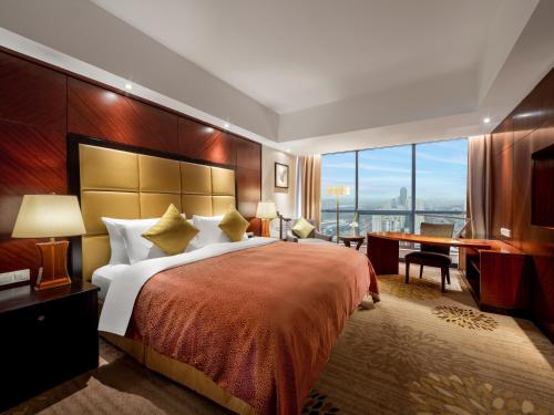 a hotel room with a large bed and a desk at Songjiang New Century Grand Hotel Shanghai in Songjiang