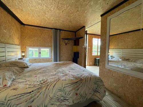 a bedroom with a large bed and a mirror at Le Cabanon in Dangeau