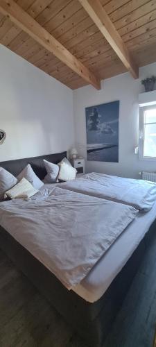 a large bed in a bedroom with a wooden ceiling at Haus Nordwind in Bedekaspel