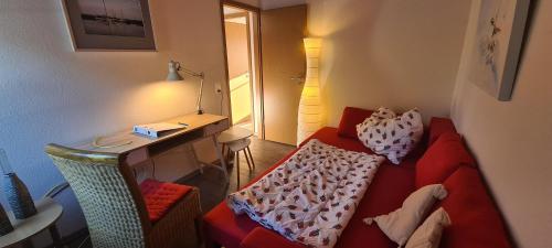 a living room with a red couch and a desk at Haus Nordwind in Bedekaspel