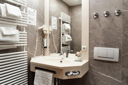 ein Bad mit einem Waschbecken und einem Spiegel in der Unterkunft Hotel Zu den Drei Kronen in Donauwörth