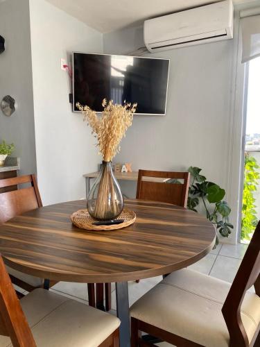 a dining room table with a vase of flowers on it at Centro histórico Downtown Depto completo alberca climatizada AC parking free seguridad 24 hras in Guadalajara