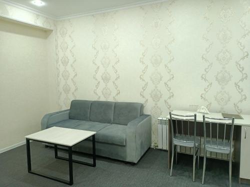 een woonkamer met een bank en een tafel en stoelen bij ЭДЕМ in Taraz