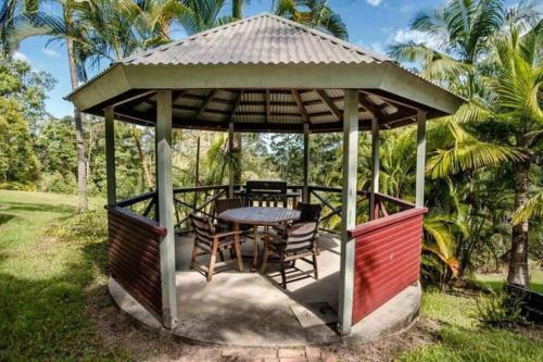 a gazebo with a table and chairs at Birdsong Train Carriage Cabin with Outdoor Bath in Palmwoods