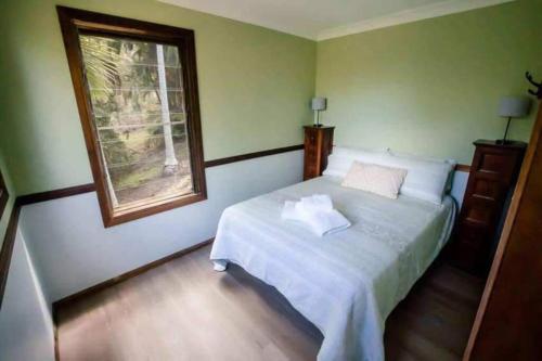 a bedroom with a white bed with a window at Birdsong Train Carriage Cabin with Outdoor Bath in Palmwoods