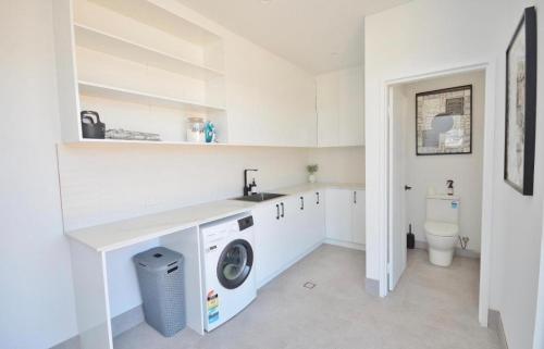 a white laundry room with a washer and dryer at Off The Hook Kalbarri in Kalbarri