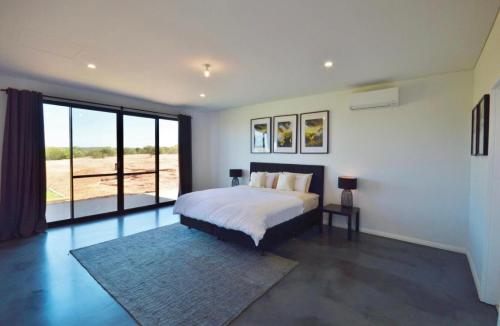 a bedroom with a bed and a large window at Off The Hook Kalbarri in Kalbarri