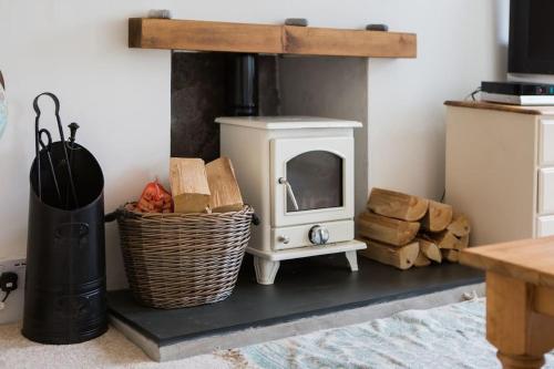 a room with a stove and a basket of logs at Charming Cornish Cottage in the heart of St Agnes in St. Agnes