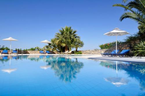 a large swimming pool with chairs and umbrellas at Elounda Living Residences in Elounda