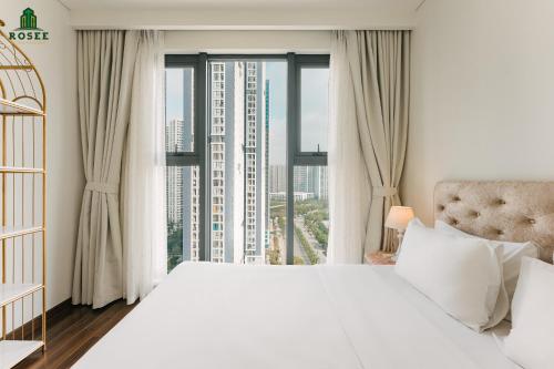 - une chambre avec un grand lit blanc et une grande fenêtre dans l'établissement Rosee House - Luxury apartment in Vinhomes Smart City, à Nam Tu Liem
