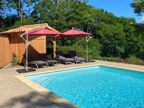 a swimming pool with two umbrellas and chairs next to at Maison Vallée Vue avec piscine chauffée in Castelnaud La Chapelle