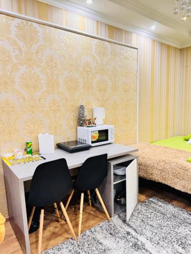 een kamer met een bureau met 2 stoelen en een bed bij Apartments in City Center in Chişinău
