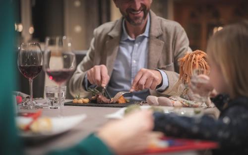 un hombre sentado en una mesa con un plato de comida en Hotel Alpenhof, en Rasun di Sotto