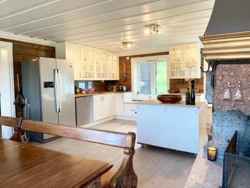 eine Küche mit einem Kühlschrank und einem Tisch darin in der Unterkunft Eventyrlig Tømmerhytte på Gårdstun in Vinstra