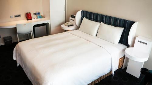 a hotel room with a large bed with white sheets at Ximen Airline Hotel in Taipei