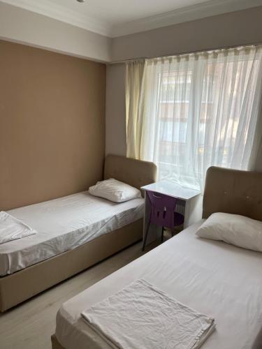 een kamer met 2 bedden, een tafel en een raam bij Safranbolu student hostel woman only in Karabük