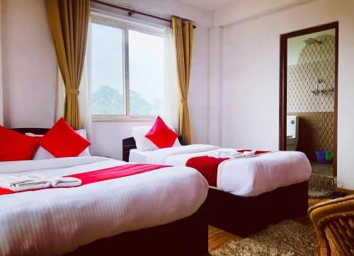 two beds in a hotel room with red pillows at Mahendra moktan in Dhulikhel