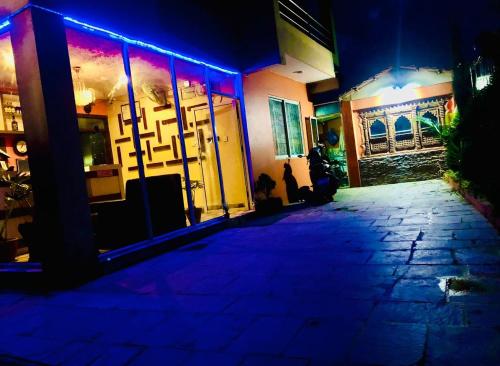 un edificio de noche con luces azules y moradas en Mahendra moktan en Dhulikhel