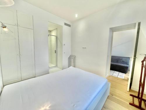 a white bedroom with a bed and a mirror at Jaurès Home by Welcome to Cannes in Cannes