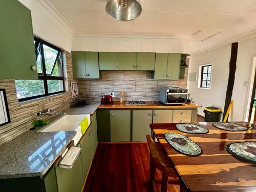 eine Küche mit grünen Schränken und einem Holztisch in der Unterkunft Cosy one bedroom garden cottage in Tugela Mouth
