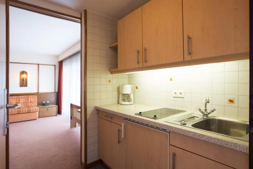 a kitchen with wooden cabinets and a sink at Apartmenthaus Brixen & Haus Central in Brixen im Thale