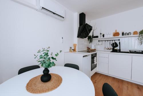 a white kitchen with a table with a vase on it at Apartman Vista in Daruvar