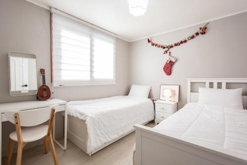 1 dormitorio con 2 camas, escritorio y guitarra en Ria House en Goyang