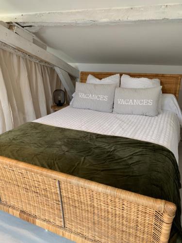 Una gran cama de mimbre con almohadas encima. en Maison de famille 24 en Trélissac