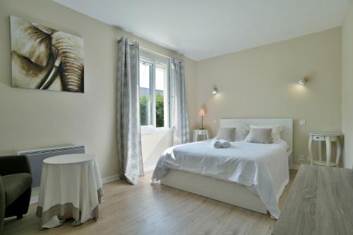ein weißes Schlafzimmer mit einem Bett und einem Fenster in der Unterkunft Villa des Daules in Cancale