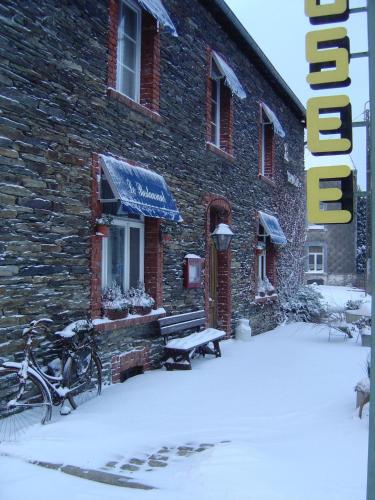 a building with a bench in the snow at La Remise - Les Chambres in Neufchâteau