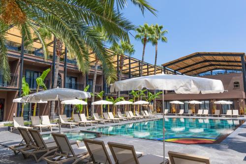 a swimming pool with lounge chairs and umbrellas at Golden Sun Hotel Adult Only in Beldibi