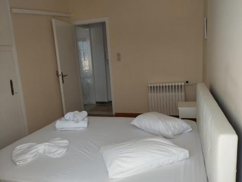 ein weißes Bett mit zwei Kissen und Handtüchern darauf in der Unterkunft Ionias Penthouse in Korinthos