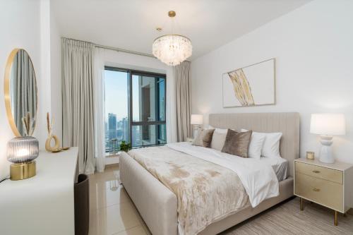 a white bedroom with a large bed and a window at Prestige Living 2BR with Full Burj Khalifa and Fountain View by Auberge in Dubai