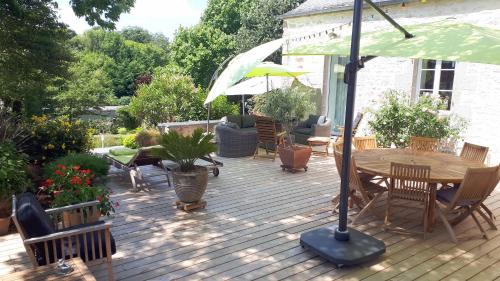 una terraza de madera con mesa, sillas y sombrilla en Le Vieux Couvent & SPA, en Sibiril