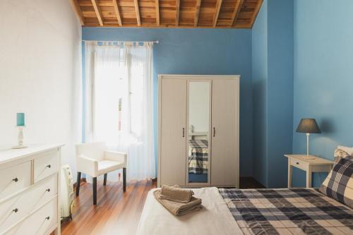 una camera da letto con pareti blu e un letto e una sedia di WelcomeBuddy - O Moinho (Furnas Spring Water) a Furnas