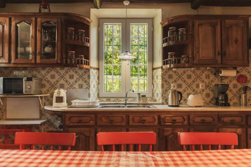 a kitchen with wooden cabinets and red chairs at O Moinho (Furnas Hot Springs) in Furnas