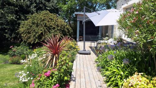 - un jardin avec une passerelle en bois et un parasol dans l'établissement Le Vieux Couvent & SPA, à Sibiril
