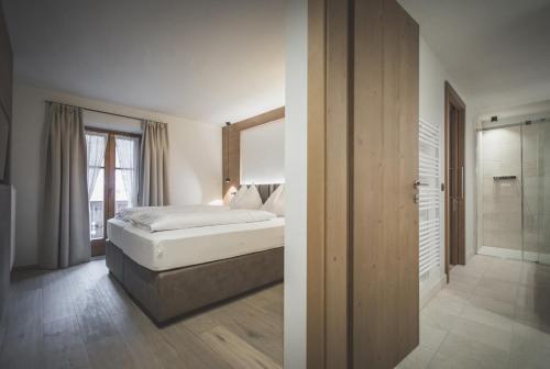 a bedroom with a bed and a walk in shower at Hotel Alpenhof in Rasùn di Sotto