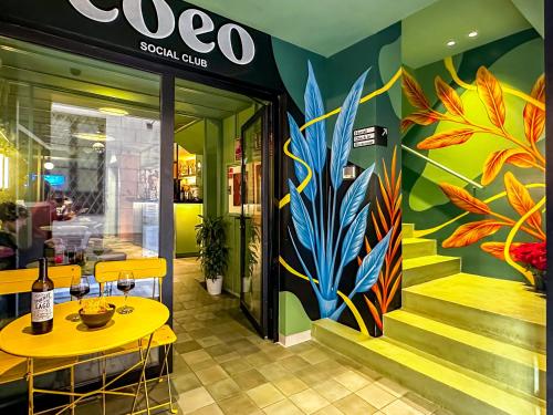 a restaurant with a yellow table and a colorful mural at COEO Pod Hostel - Part of COEO Experience in Málaga