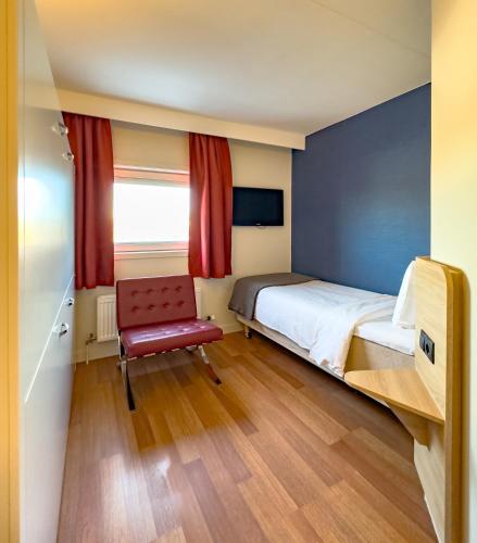 a bedroom with a bed and a red chair at Good Morning Lund in Lund