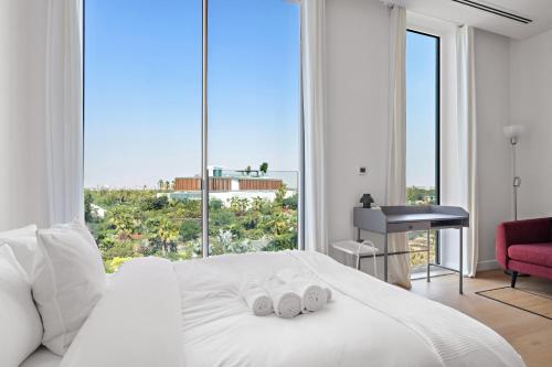 a bedroom with a white bed with a large window at Cosy Studio in Al Barari in Dubai