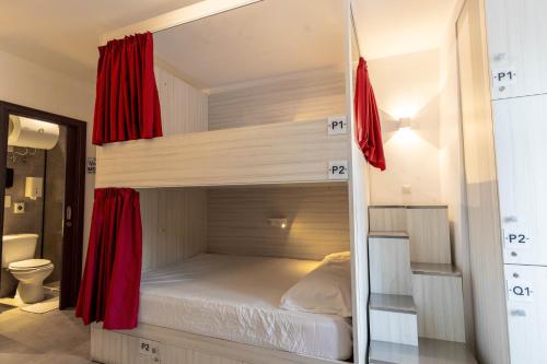 um quarto com um beliche com cortinas vermelhas em The Rose Hostel em St. Julian's